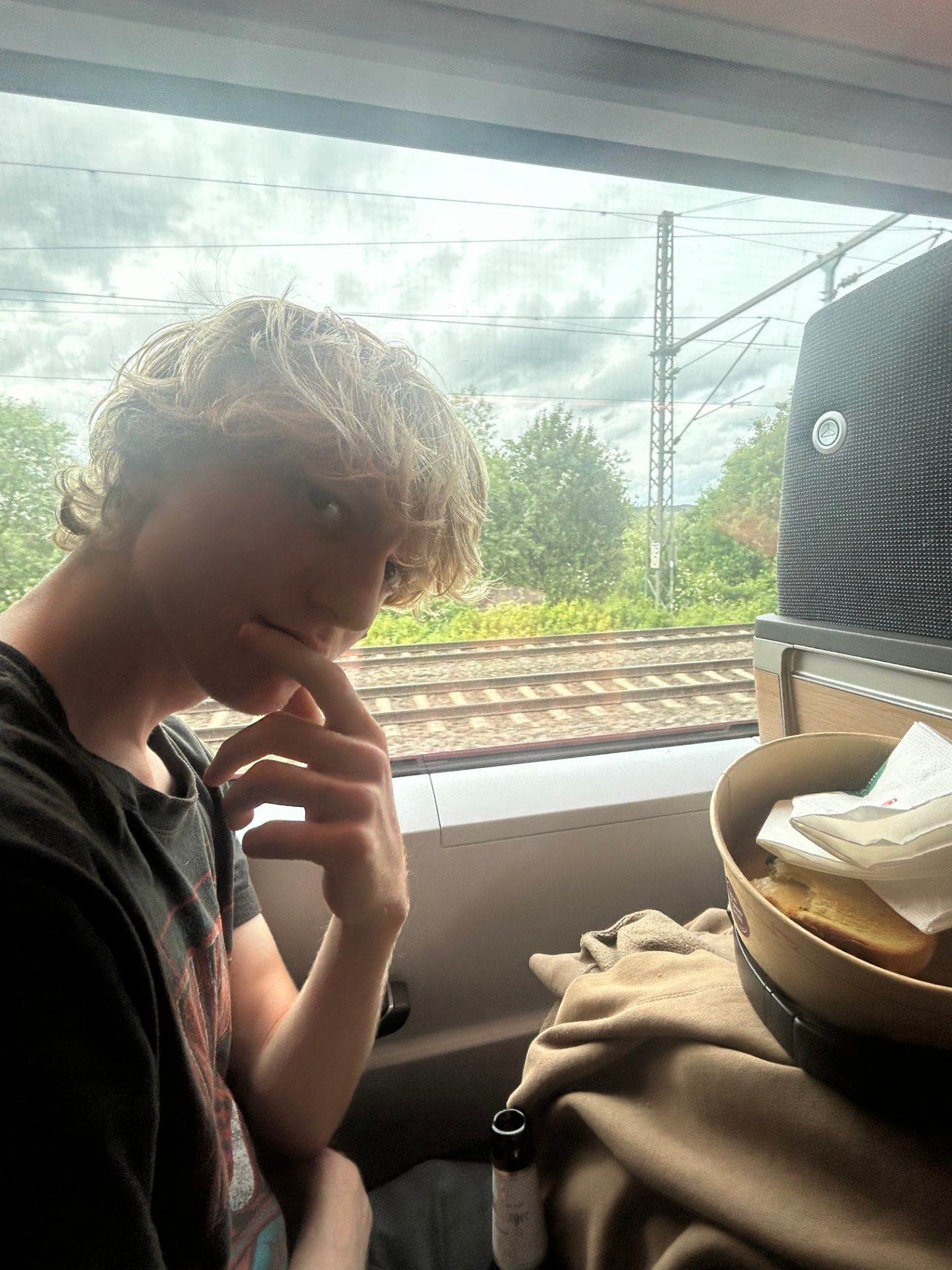 A backpacker on a European train with food on the tray table