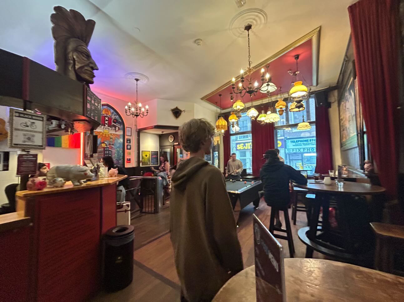 Interior of an Amsterdam hostel bar with a pool table and warm lamps