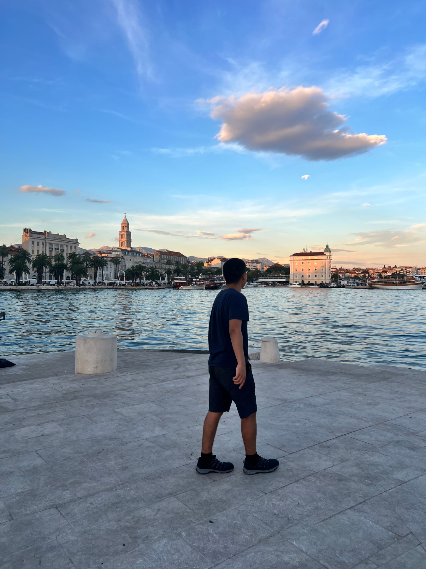 Backpacker on the Split waterfront at golden hour looking at the old town